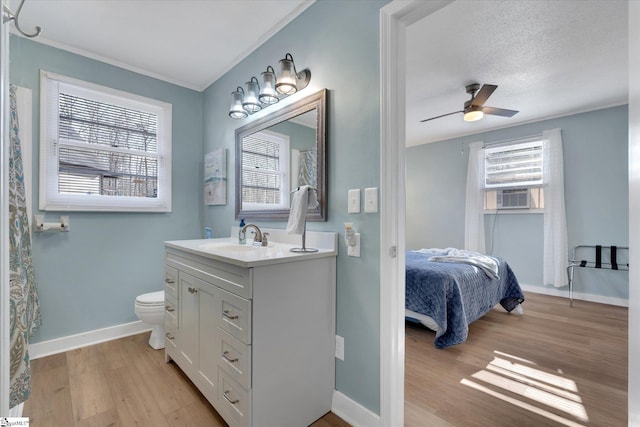 bathroom featuring hardwood / wood-style flooring, ceiling fan, cooling unit, vanity, and toilet