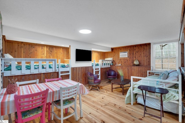 dining space featuring light hardwood / wood-style flooring, wooden walls, and a wall mounted AC