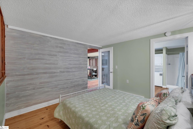 bedroom featuring wood-type flooring, wooden walls, and a textured ceiling