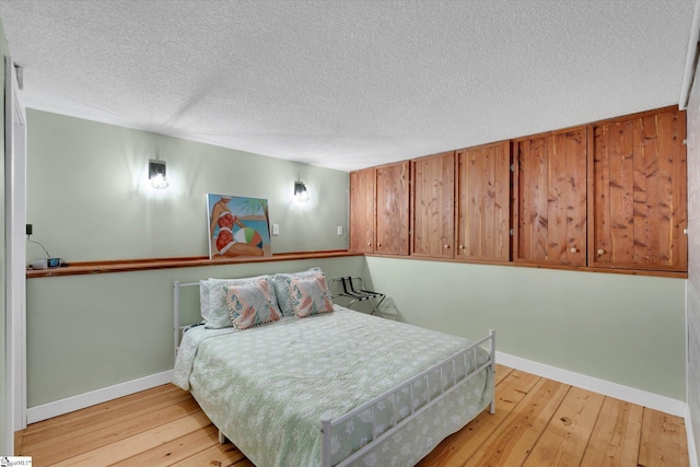 bedroom with light hardwood / wood-style floors and a textured ceiling