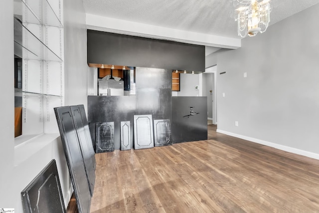 interior space with beamed ceiling, a chandelier, hardwood / wood-style floors, and a textured ceiling