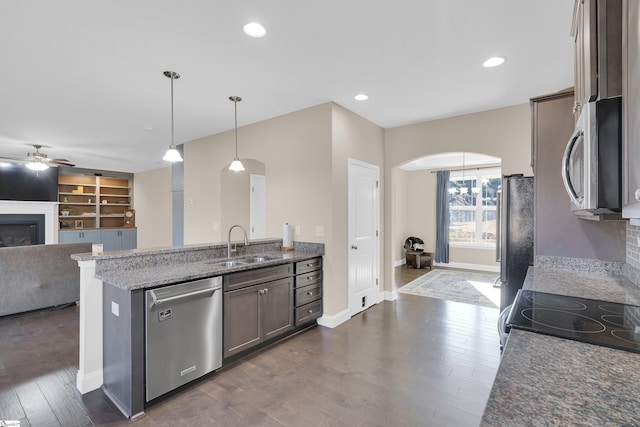 kitchen featuring pendant lighting, sink, appliances with stainless steel finishes, dark brown cabinets, and dark stone counters