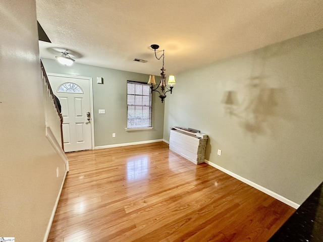 entrance foyer featuring a textured ceiling, a notable chandelier, and light wood-type flooring