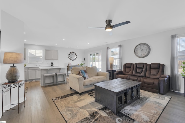 living room with sink, plenty of natural light, ceiling fan, and light wood-type flooring