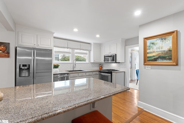 kitchen featuring white cabinetry, sink, a kitchen breakfast bar, stainless steel appliances, and light stone countertops