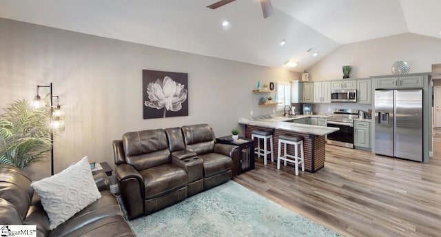 living room with lofted ceiling, sink, ceiling fan, and light wood-type flooring