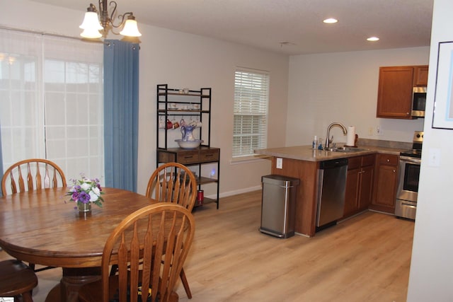 14 Heatherfield Dr, Simpsonville, SC 29680 - kitchen featuring light wood-style flooring, a peninsula, appliances with stainless steel finishes, a sink, and brown cabinets