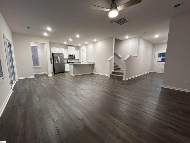 unfurnished living room with dark hardwood / wood-style flooring and ceiling fan