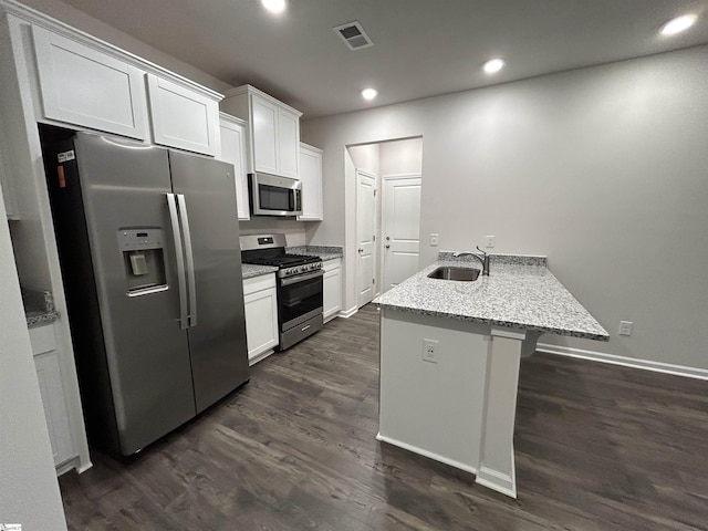 kitchen with dark hardwood / wood-style floors, sink, white cabinets, stainless steel appliances, and light stone countertops