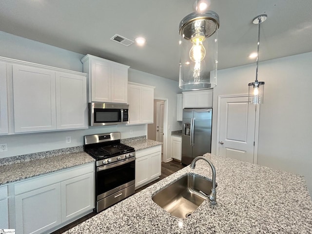 kitchen with pendant lighting, sink, white cabinetry, stainless steel appliances, and light stone countertops