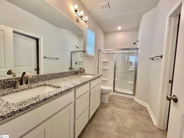 bathroom featuring tile patterned floors, vanity, toilet, and a shower with shower door