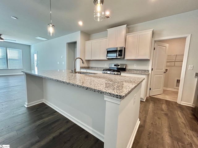 kitchen featuring a kitchen island with sink, hanging light fixtures, white cabinets, and appliances with stainless steel finishes