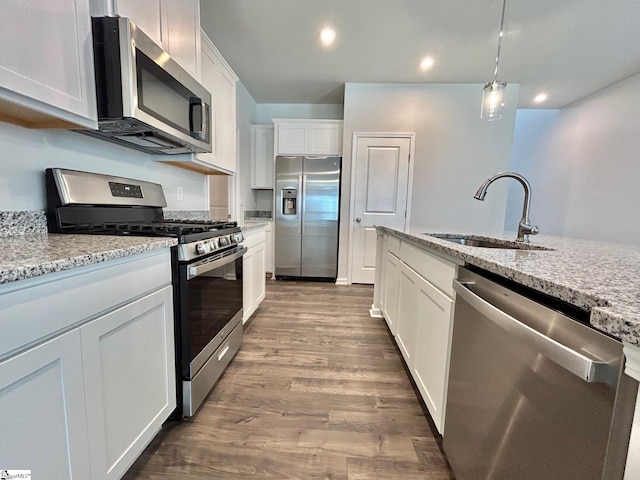 kitchen with appliances with stainless steel finishes, pendant lighting, sink, white cabinets, and light stone counters