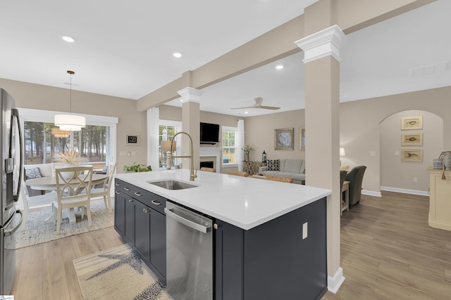 kitchen with pendant lighting, sink, appliances with stainless steel finishes, a center island with sink, and light wood-type flooring