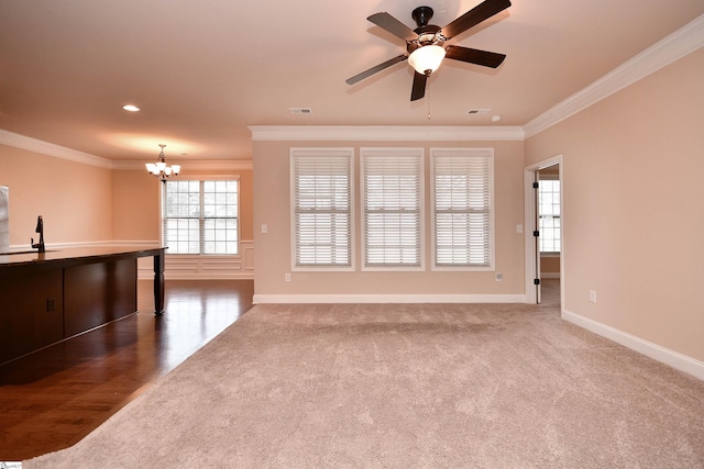 unfurnished living room featuring crown molding, ceiling fan with notable chandelier, and dark colored carpet