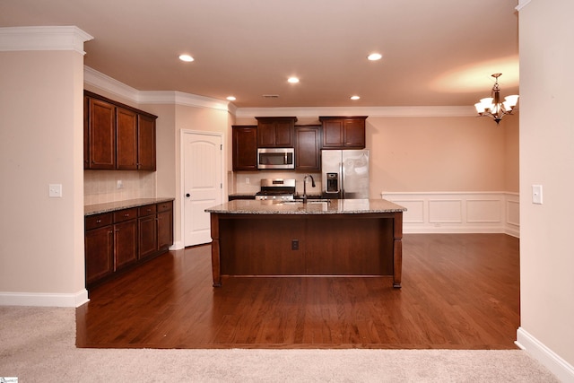 kitchen featuring sink, stainless steel appliances, light stone counters, dark brown cabinetry, and an island with sink