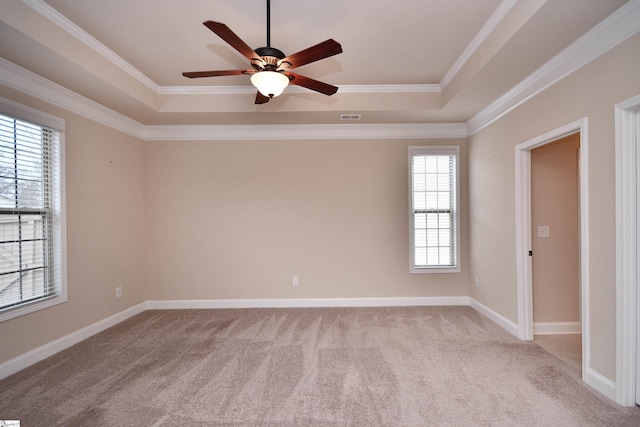 empty room with crown molding, light carpet, ceiling fan, and a tray ceiling