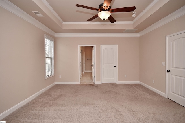 carpeted empty room featuring ornamental molding, ceiling fan, and a tray ceiling