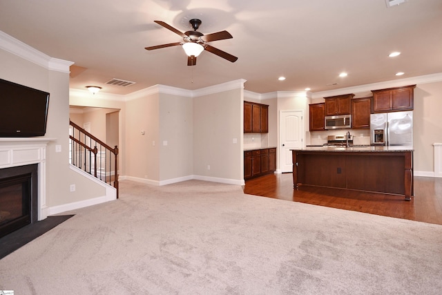 unfurnished living room with dark colored carpet, crown molding, and ceiling fan