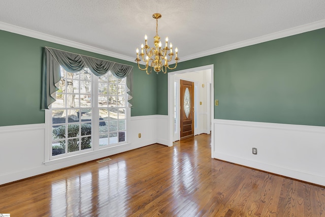 unfurnished dining area with crown molding, hardwood / wood-style floors, and a textured ceiling