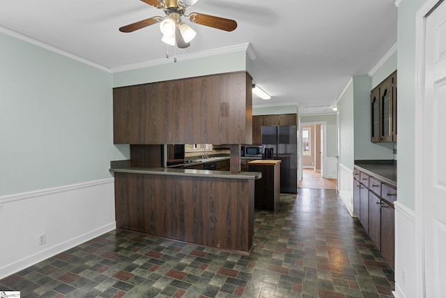 kitchen with stainless steel microwave, ceiling fan, kitchen peninsula, crown molding, and black fridge