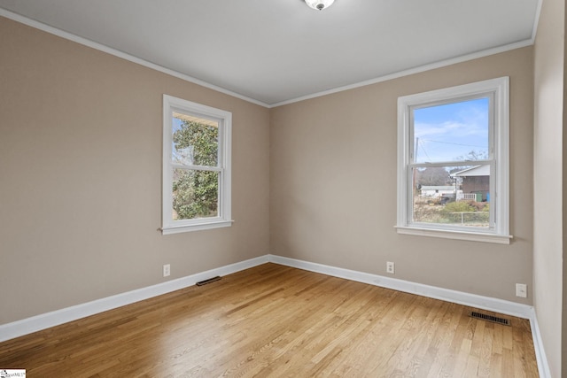 spare room with ornamental molding and light hardwood / wood-style flooring