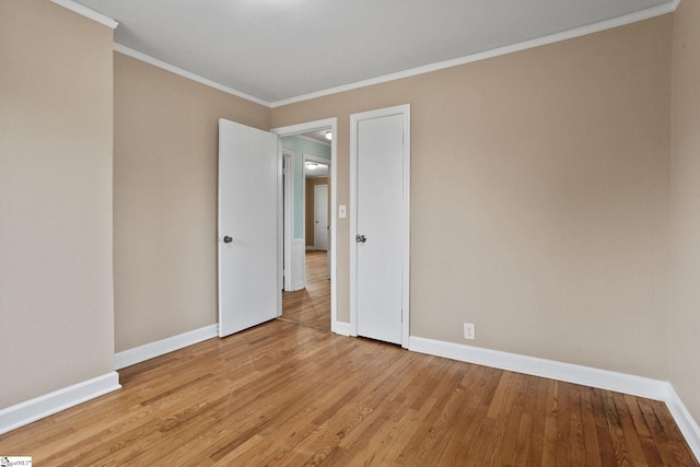 empty room with ornamental molding and light hardwood / wood-style flooring