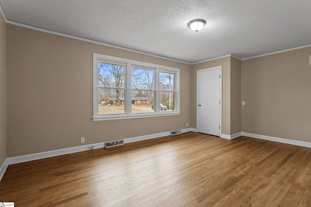empty room with ornamental molding, light hardwood / wood-style flooring, and a textured ceiling