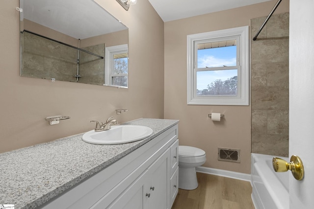 full bathroom featuring vanity, hardwood / wood-style floors, tiled shower / bath, and toilet