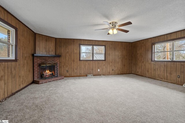 unfurnished living room with light colored carpet, a healthy amount of sunlight, a brick fireplace, and a textured ceiling