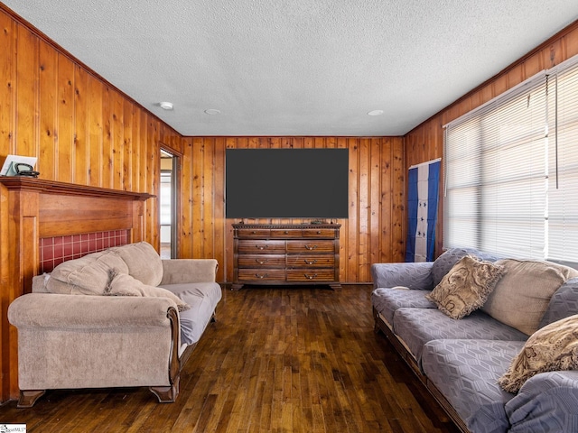 living room with dark wood-type flooring, a textured ceiling, and wood walls