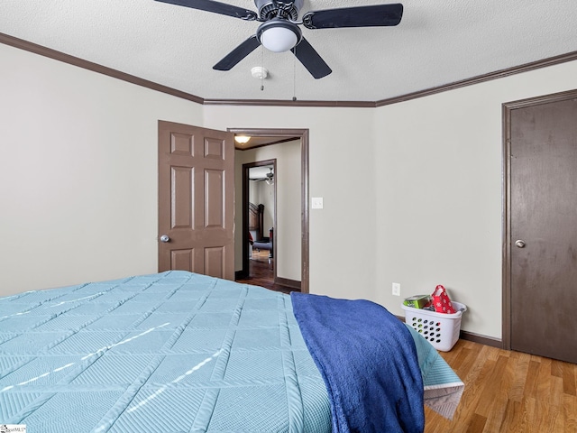 bedroom with crown molding, hardwood / wood-style floors, ceiling fan, and a textured ceiling