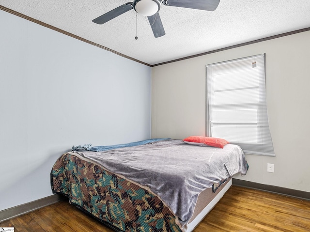 bedroom featuring ceiling fan, ornamental molding, hardwood / wood-style floors, and a textured ceiling