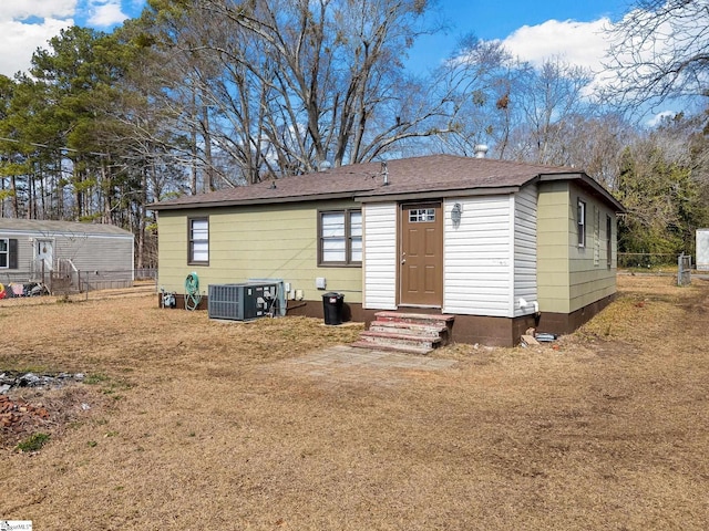 back of house with central AC and a yard