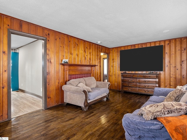 living room with dark wood-type flooring, wooden walls, and a textured ceiling