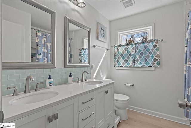 bathroom featuring tasteful backsplash, vanity, hardwood / wood-style flooring, and toilet