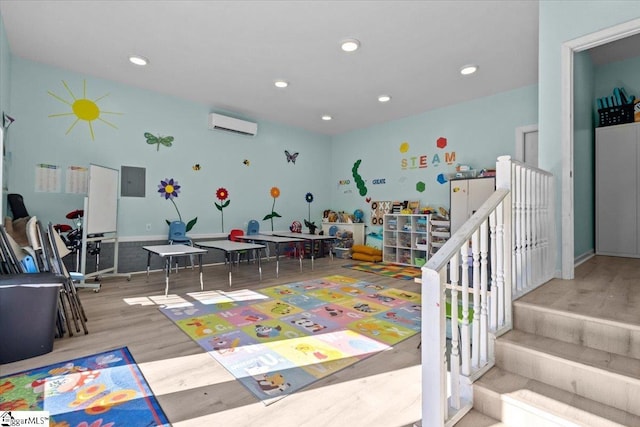 rec room featuring wood-type flooring, electric panel, and a wall unit AC