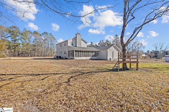 rear view of house featuring a yard and a sunroom