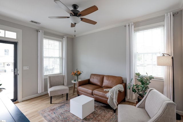 living room with light hardwood / wood-style flooring, crown molding, and plenty of natural light