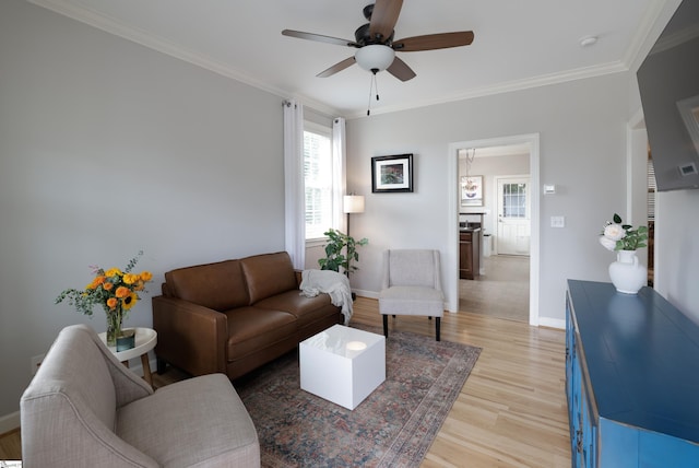 living room featuring light hardwood / wood-style flooring, ornamental molding, and ceiling fan