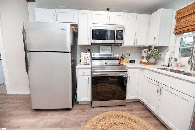 kitchen featuring sink, light hardwood / wood-style flooring, stainless steel appliances, and white cabinets