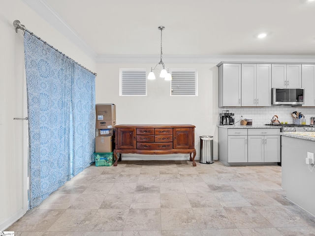 kitchen with an inviting chandelier, hanging light fixtures, ornamental molding, light stone countertops, and decorative backsplash