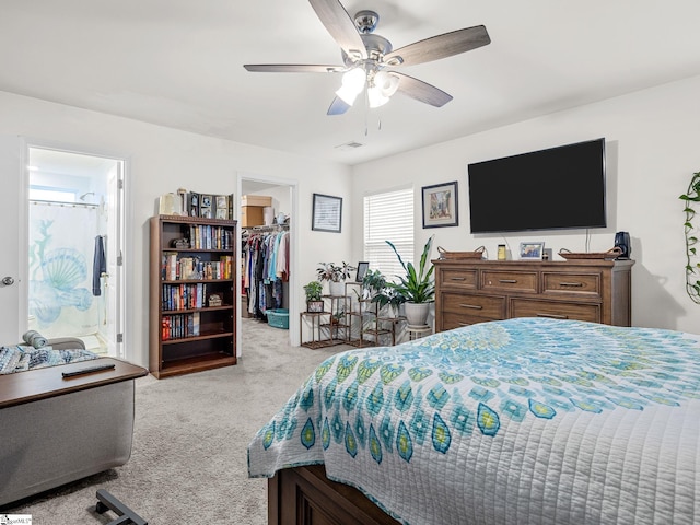 bedroom with ensuite bathroom, a spacious closet, ceiling fan, light carpet, and a closet