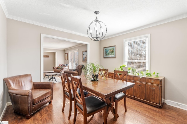 dining room with ornamental molding, wood-type flooring, a chandelier, and a textured ceiling