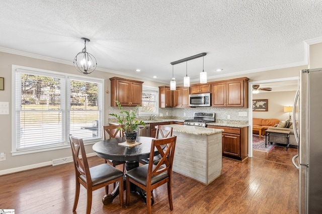 kitchen with a kitchen island, appliances with stainless steel finishes, dark hardwood / wood-style floors, and decorative light fixtures