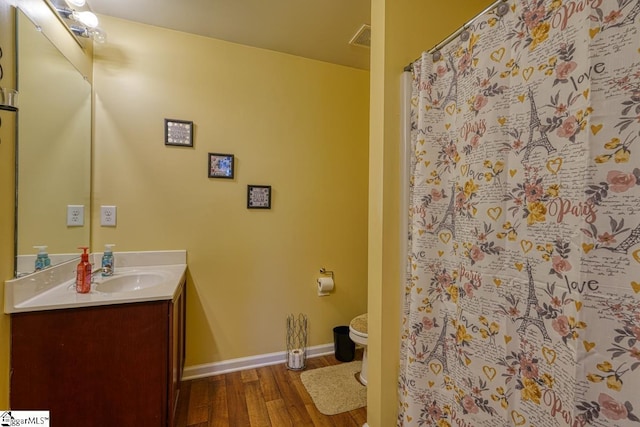 bathroom featuring wood-type flooring, toilet, and vanity