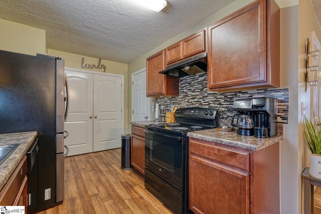 kitchen with black electric range oven, light wood-type flooring, stainless steel fridge, backsplash, and a textured ceiling