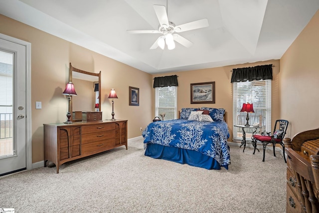 carpeted bedroom featuring a raised ceiling and ceiling fan