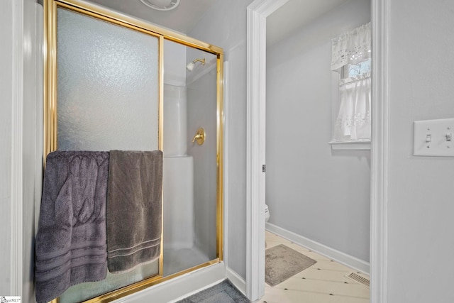 bathroom featuring toilet and a shower with shower door