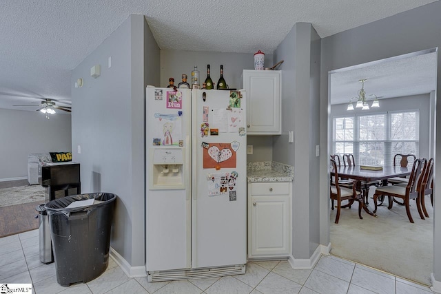 kitchen featuring white cabinetry, white refrigerator with ice dispenser, light tile patterned floors, and a textured ceiling